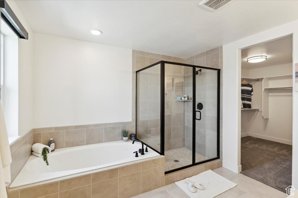 Bathroom featuring a garden tub, a stall shower, a walk in closet, and healthy amount of natural light