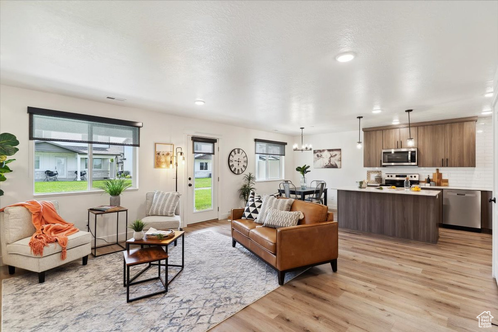 Living area featuring light wood-style flooring, plenty of natural light, recessed lighting, and a chandelier