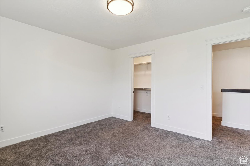 Unfurnished bedroom with carpet flooring, baseboards, a walk in closet, and a closet