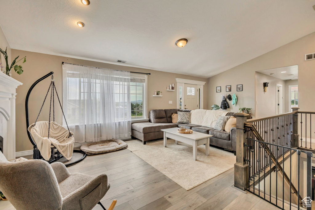 Living area with wood finished floors, plenty of natural light, lofted ceiling, and a fireplace