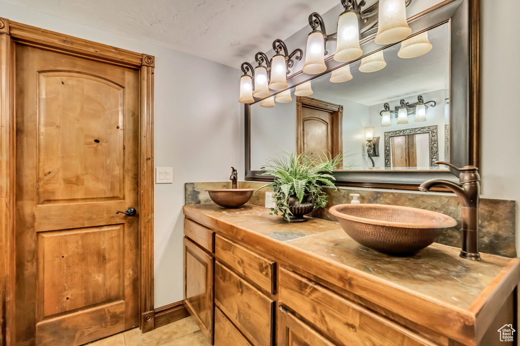 Bathroom with double vanity, tile patterned flooring, and decorative backsplash