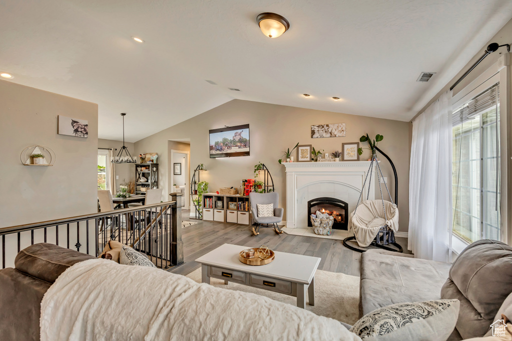 Living room with lofted ceiling, wood finished floors, a fireplace, and recessed lighting