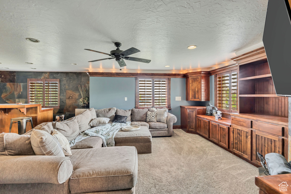 Living area with light colored carpet, a ceiling fan, recessed lighting, and a textured ceiling