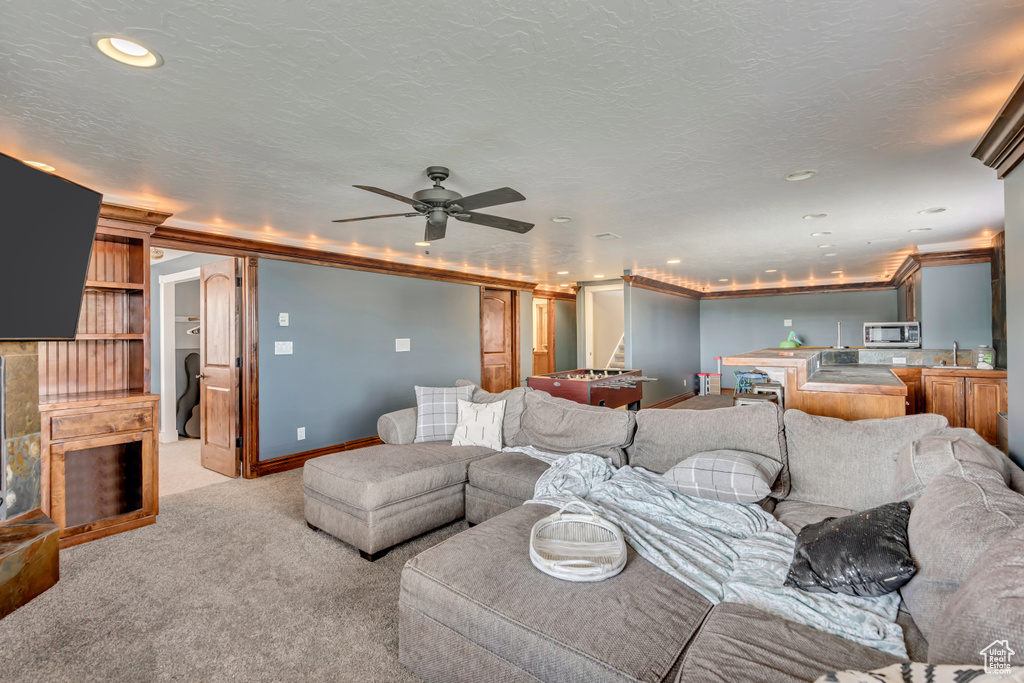 Living area featuring light colored carpet, ceiling fan, recessed lighting, and baseboards