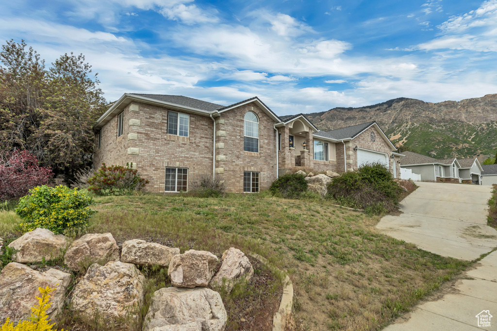 View of front of home with brick siding, driveway, a garage, and a mountain view