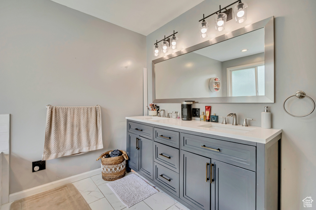 Bathroom featuring double vanity, baseboards, and marble finish flooring