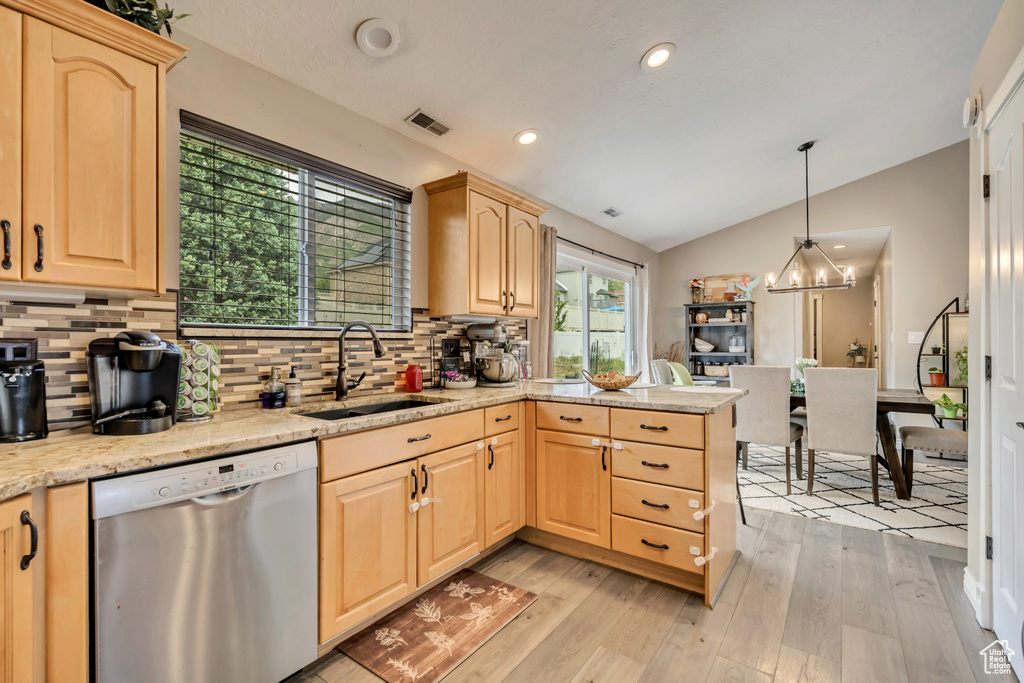 Kitchen with stainless steel dishwasher, light brown cabinetry, a sink, lofted ceiling, and backsplash