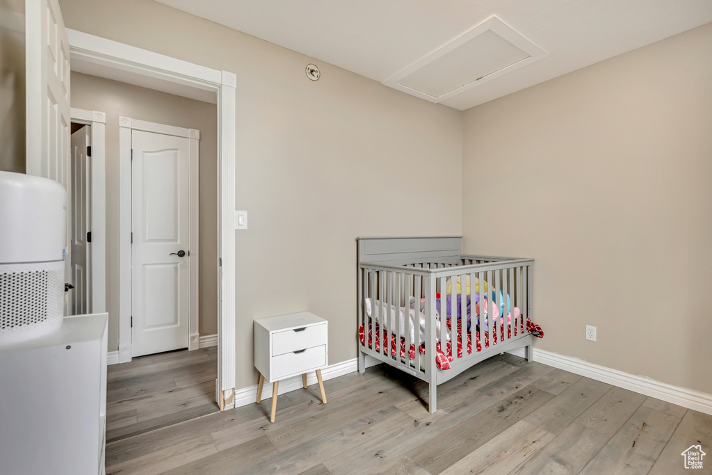 Bedroom with light wood-style flooring, baseboards, and a nursery area