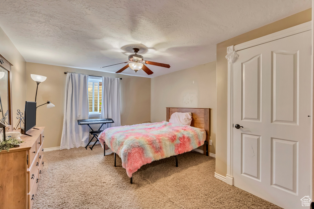 Bedroom with light carpet, baseboards, a textured ceiling, and ceiling fan