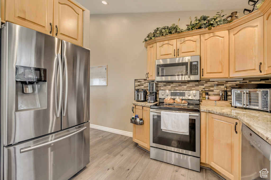 Kitchen featuring stainless steel appliances, light brown cabinetry, backsplash, baseboards, and recessed lighting
