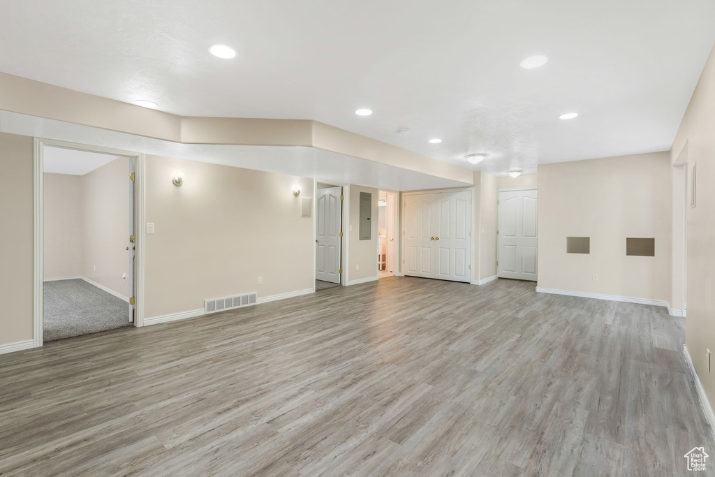 Unfurnished living room with light wood-style flooring, recessed lighting, baseboards, and electric panel