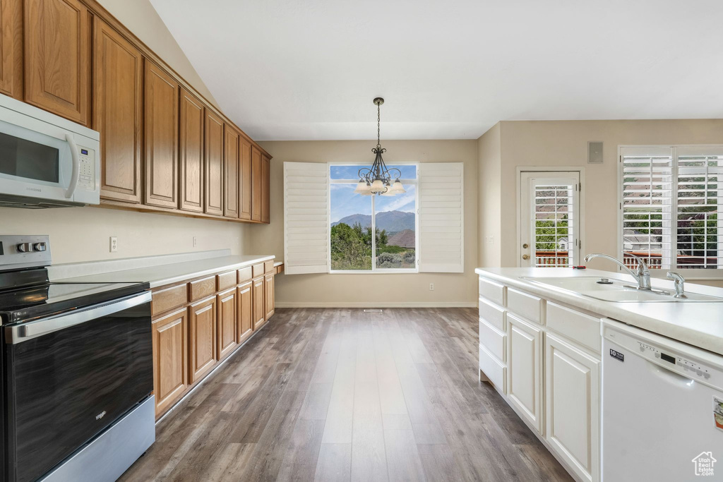 Kitchen with white appliances, a sink, a chandelier, dark wood-style floors, and light countertops