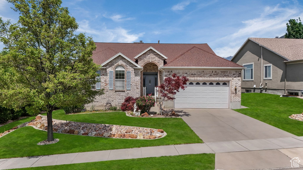 View of front of house featuring a front lawn, concrete driveway, a garage, and brick siding