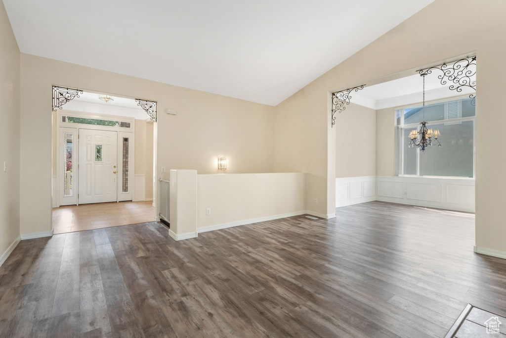 Foyer featuring a chandelier, vaulted ceiling, dark wood finished floors, and baseboards