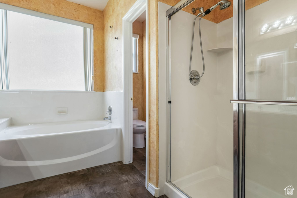 Bathroom with a bath, a shower stall, wood finished floors, and toilet
