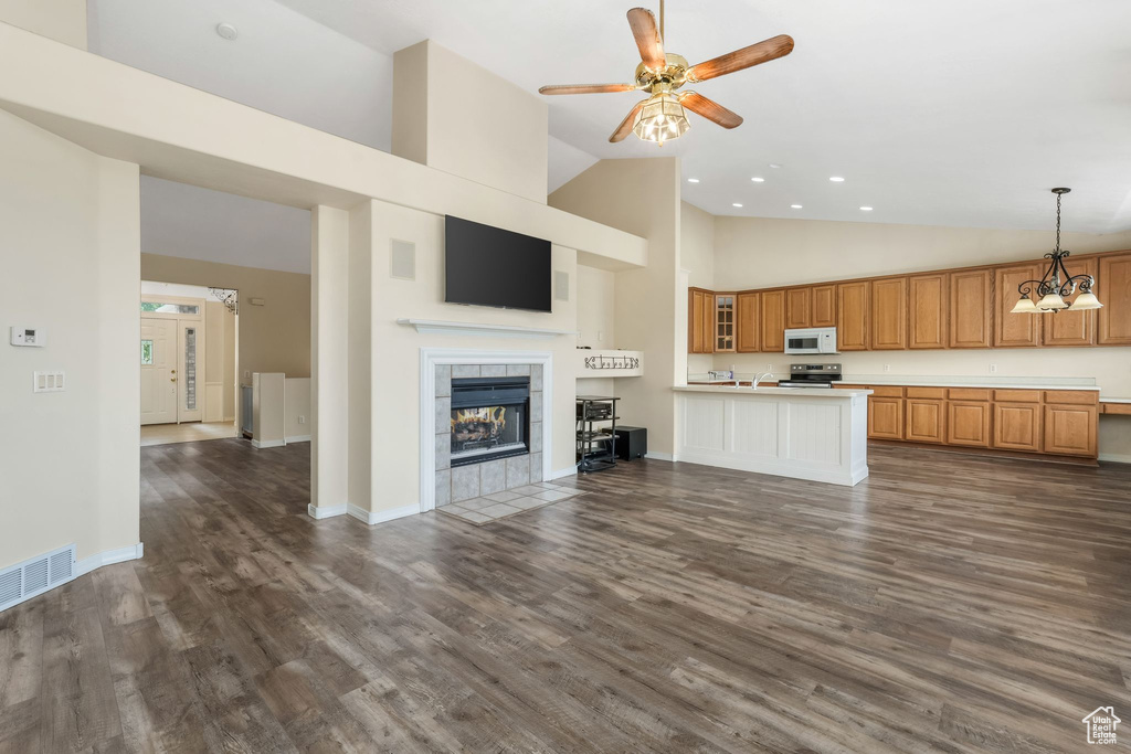 Unfurnished living room with high vaulted ceiling, ceiling fan, dark wood-style flooring, recessed lighting, and a tiled fireplace
