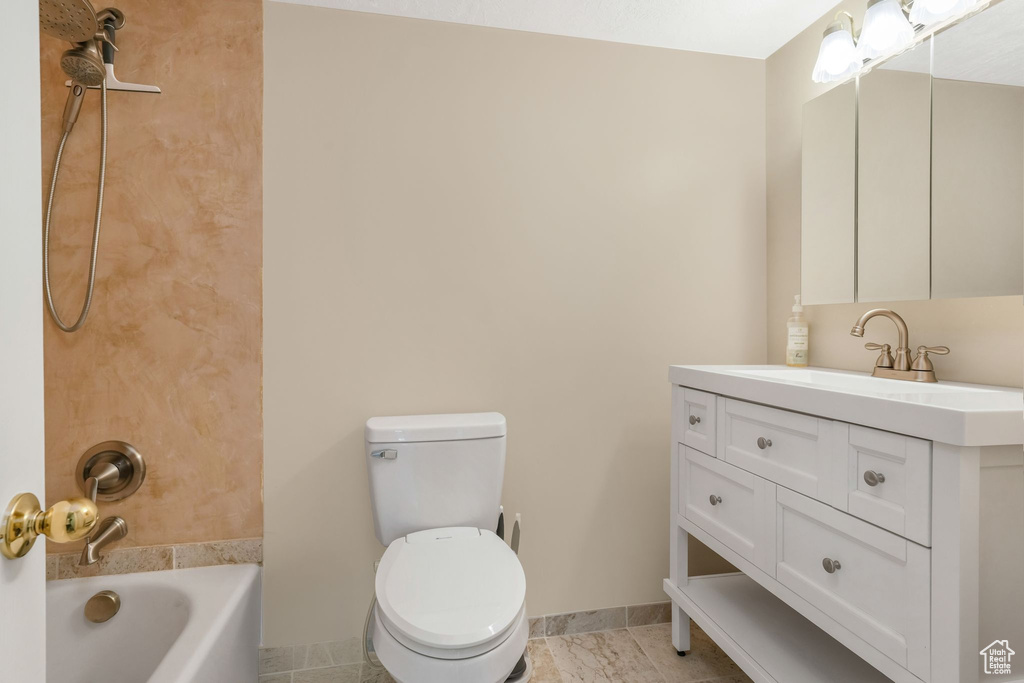 Bathroom with vanity, baseboards, washtub / shower combination, and toilet