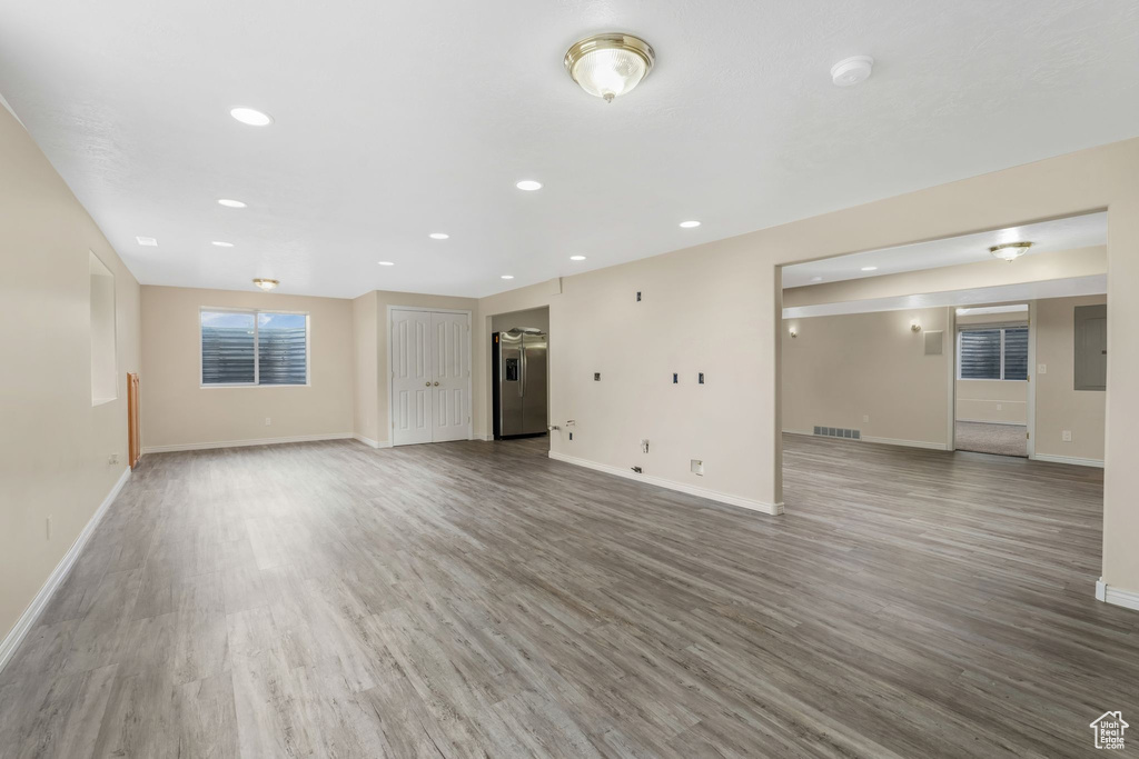 Unfurnished living room featuring baseboards, wood finished floors, recessed lighting, and electric panel