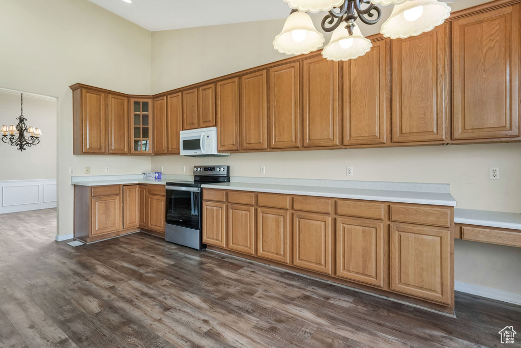 Kitchen with electric range, white microwave, a chandelier, a high ceiling, and brown cabinets