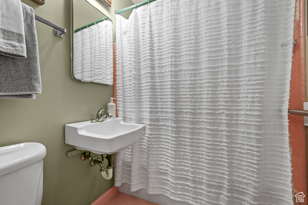 Full bath featuring toilet, curtained shower, and a sink