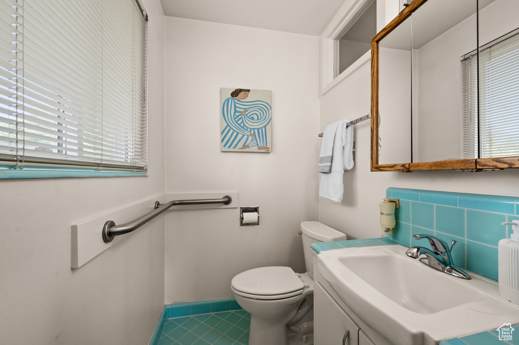 Bathroom featuring vanity, toilet, baseboards, and tile patterned floors