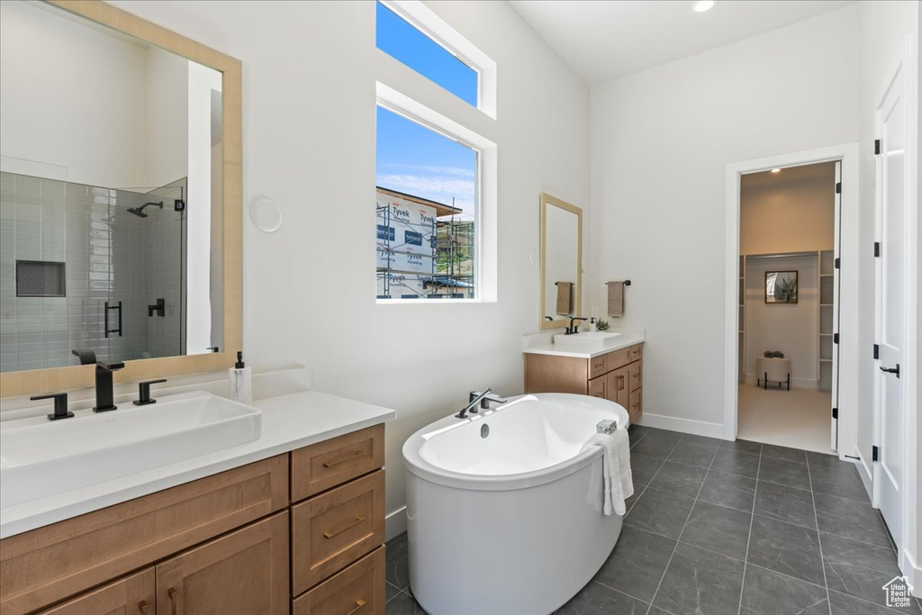 Bathroom with a shower stall, two vanities, a soaking tub, and tile patterned flooring