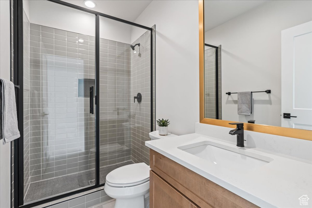 Bathroom with vanity, a shower stall, and toilet
