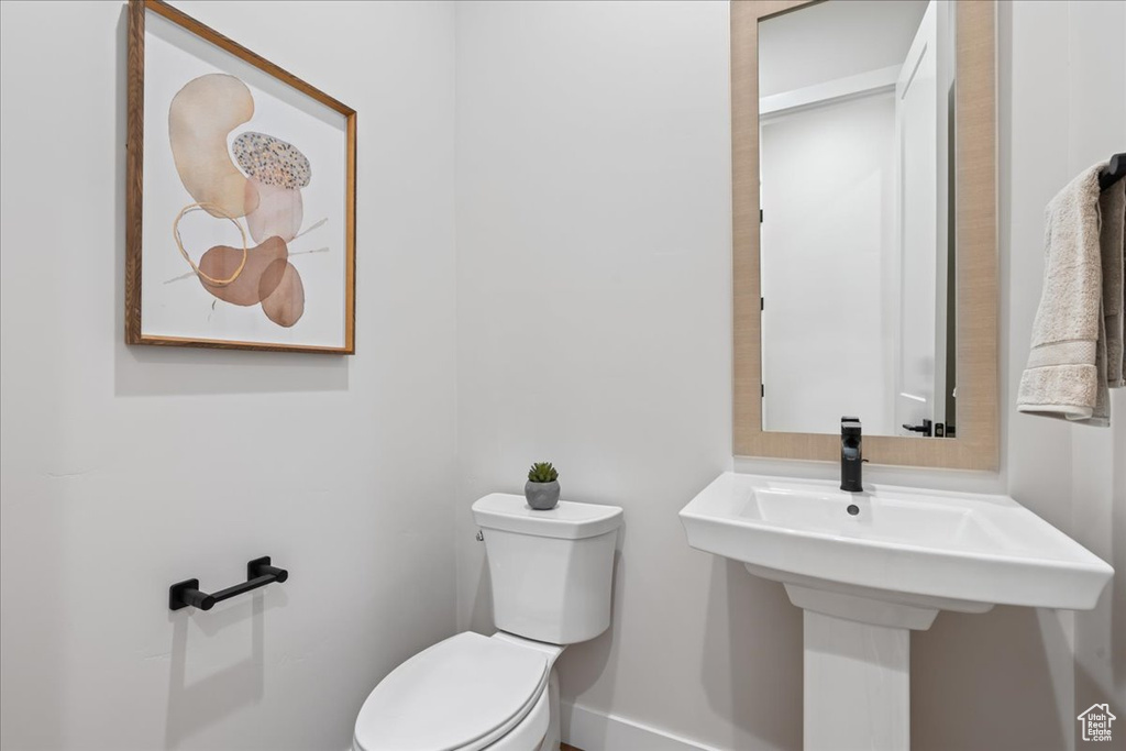 Bathroom with toilet, baseboards, and a sink
