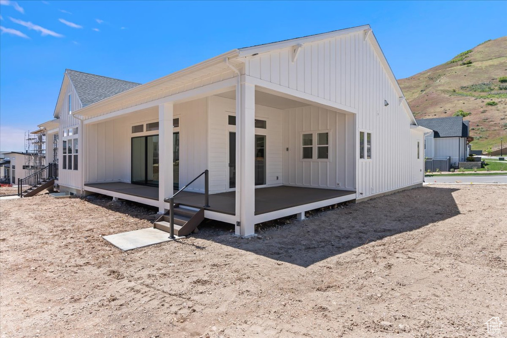 Back of property featuring board and batten siding, a mountain view, and a shingled roof