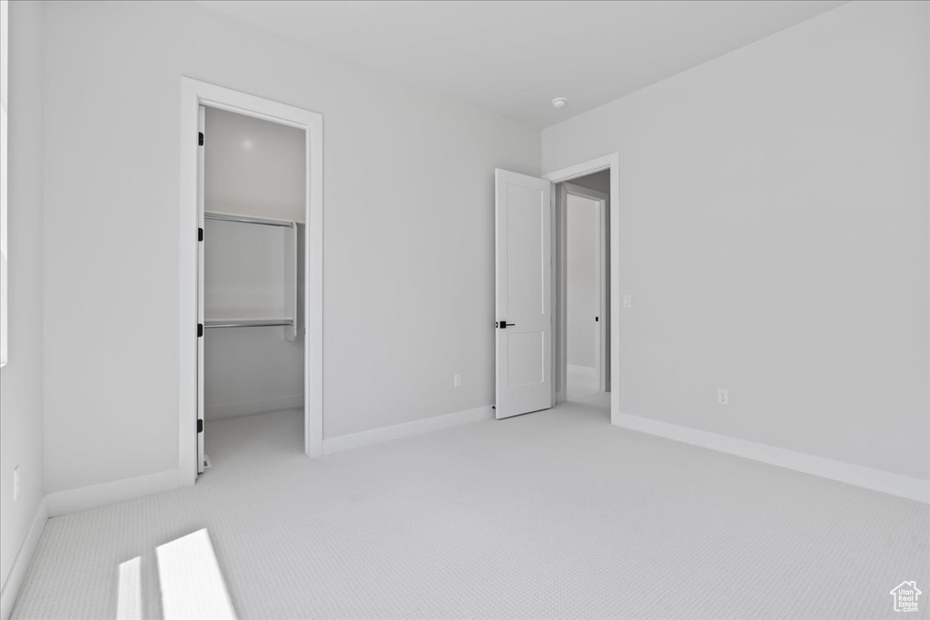 Unfurnished bedroom featuring carpet floors, baseboards, a walk in closet, and a closet