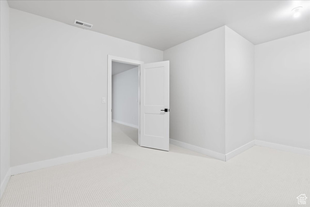 Additional living space featuring light colored carpet and baseboards