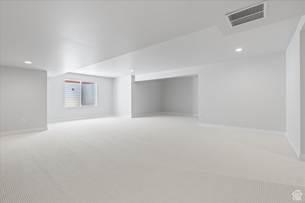 Below grade area with baseboards, light colored carpet, and recessed lighting