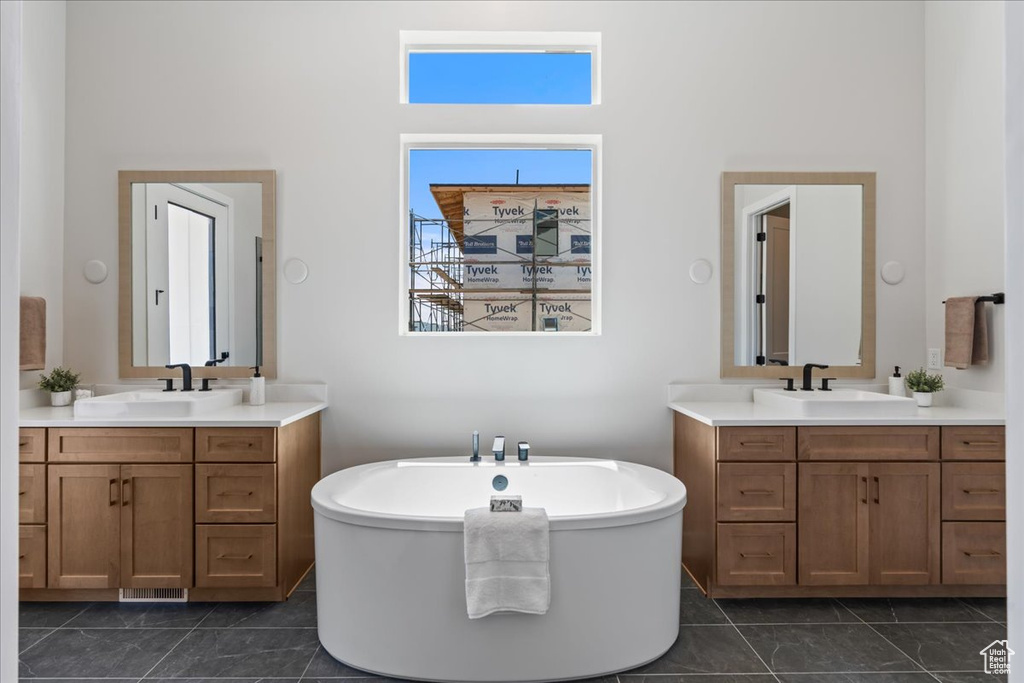 Bathroom featuring a soaking tub, two vanities, and a high ceiling