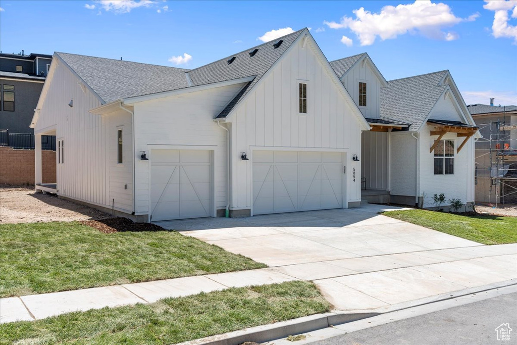 Modern farmhouse style home with roof with shingles, board and batten siding, concrete driveway, and a garage
