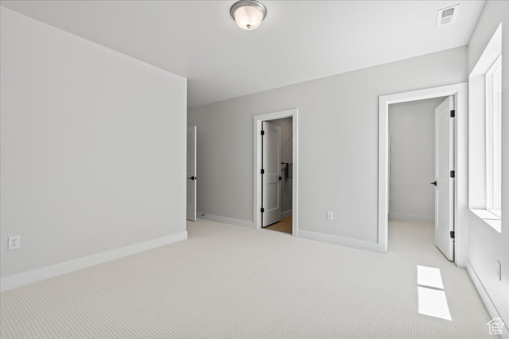 Unfurnished bedroom with a spacious closet, carpet flooring, baseboards, and a closet