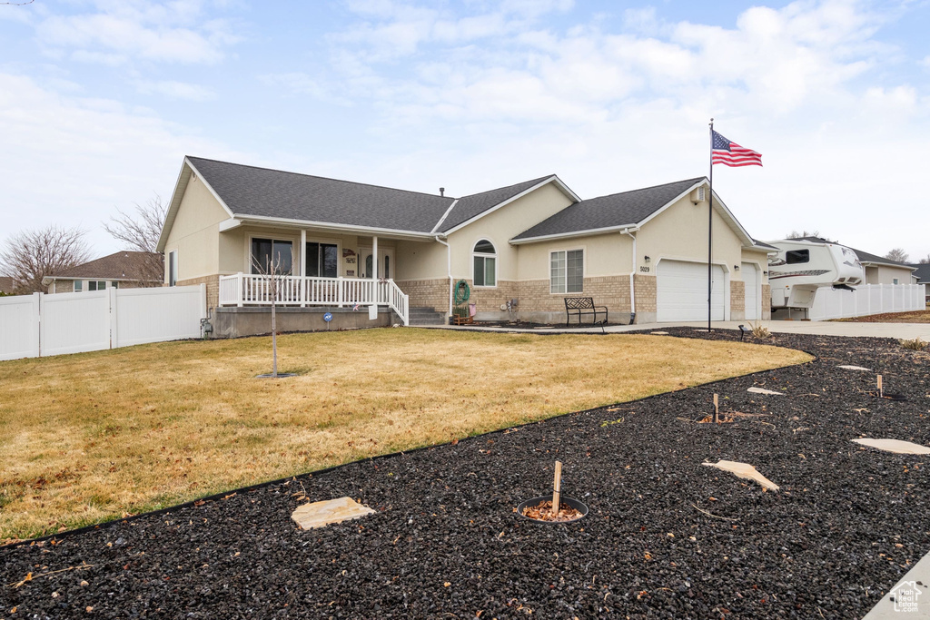 Ranch-style home featuring covered porch, stucco siding, an attached garage, and driveway