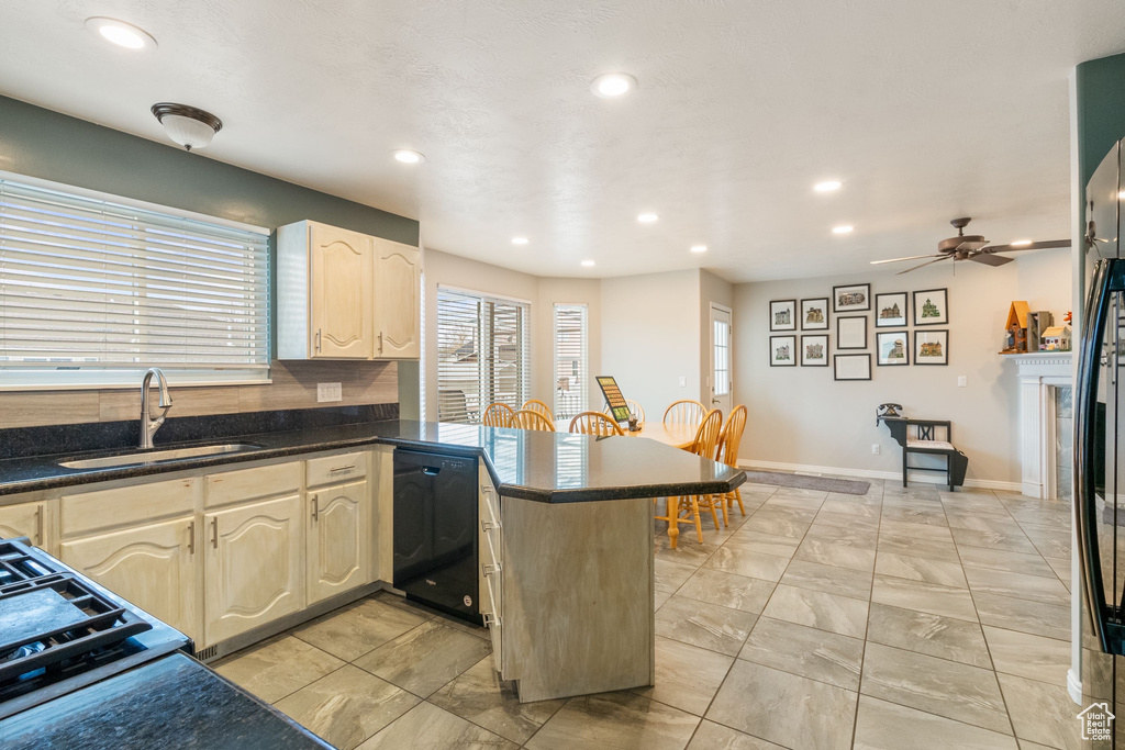 Kitchen featuring black dishwasher, a sink, a peninsula, dark countertops, and recessed lighting