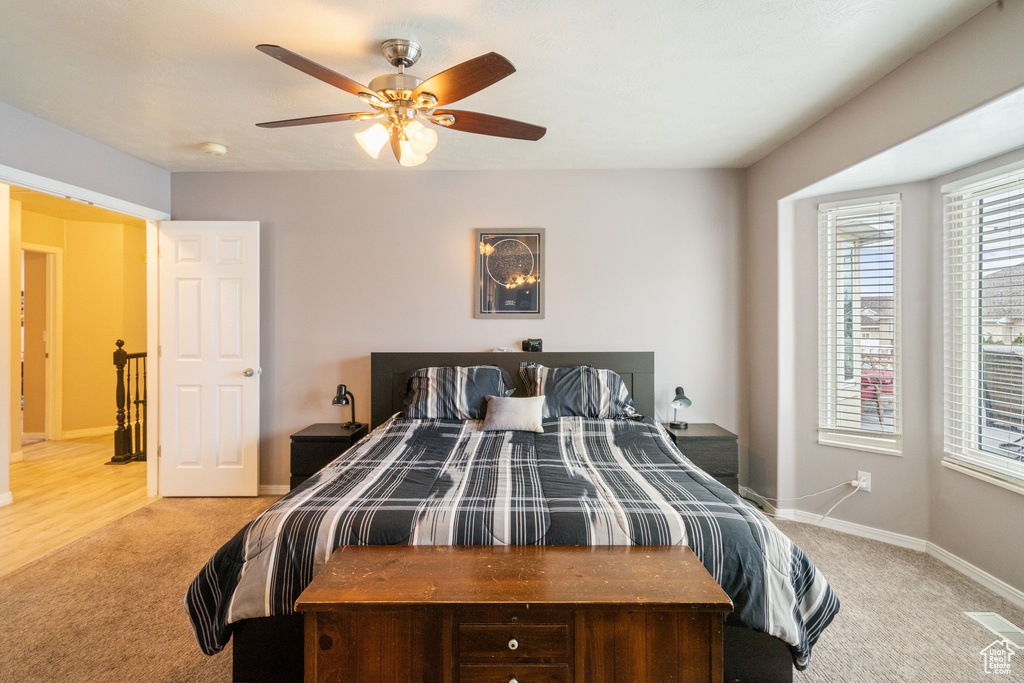 Bedroom featuring light carpet, ceiling fan, and baseboards
