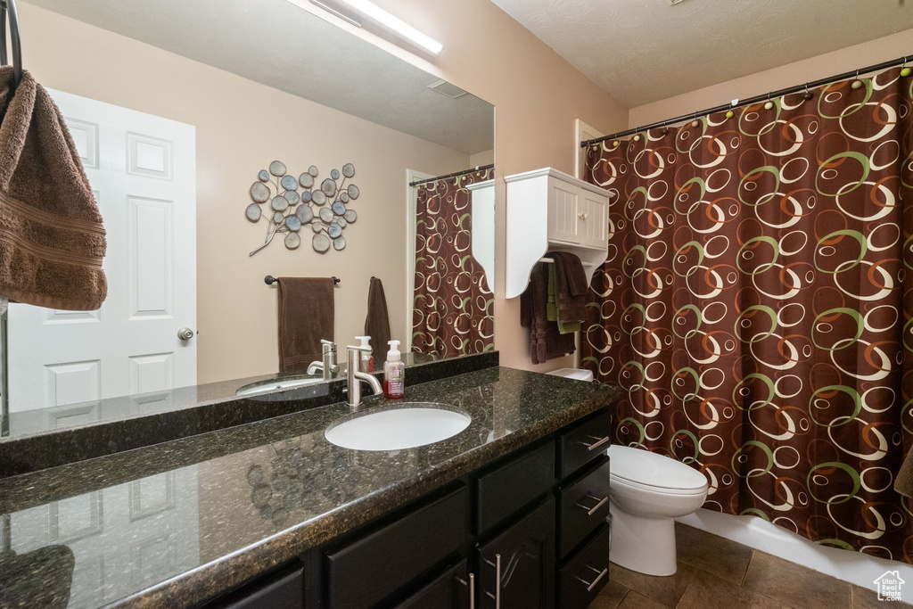 Bathroom with vanity, toilet, and curtained shower