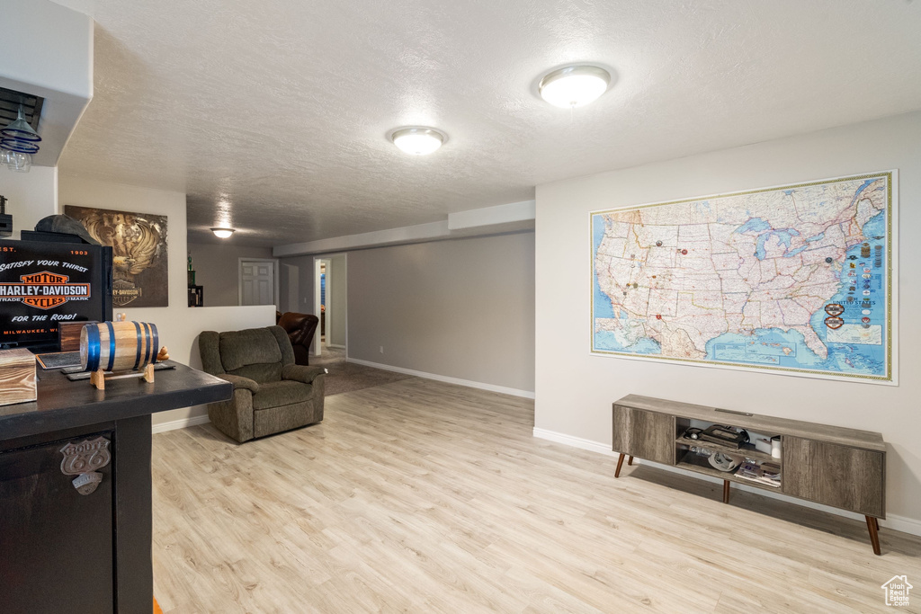 Living area featuring wood finished floors, a textured ceiling, and baseboards