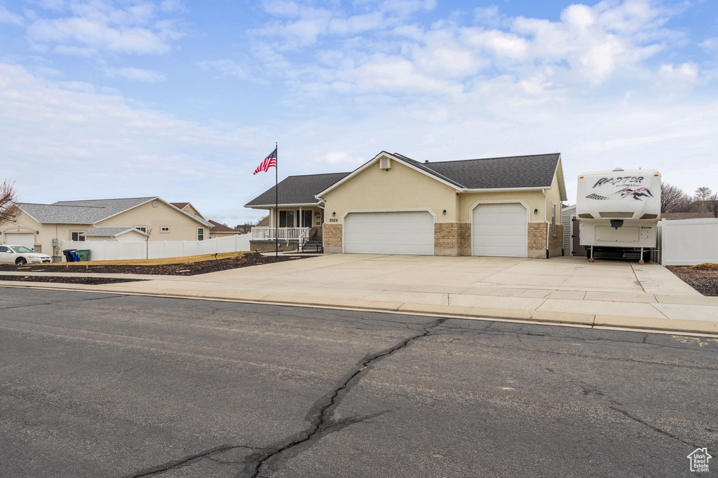View of front of property with a garage, driveway, brick siding, stucco siding, and roof with shingles