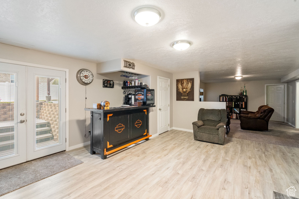 Sitting room with wood finished floors, french doors, baseboards, and a textured ceiling