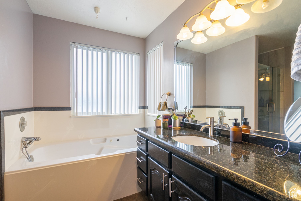 Full bath with vanity, a bath, plenty of natural light, and a shower stall