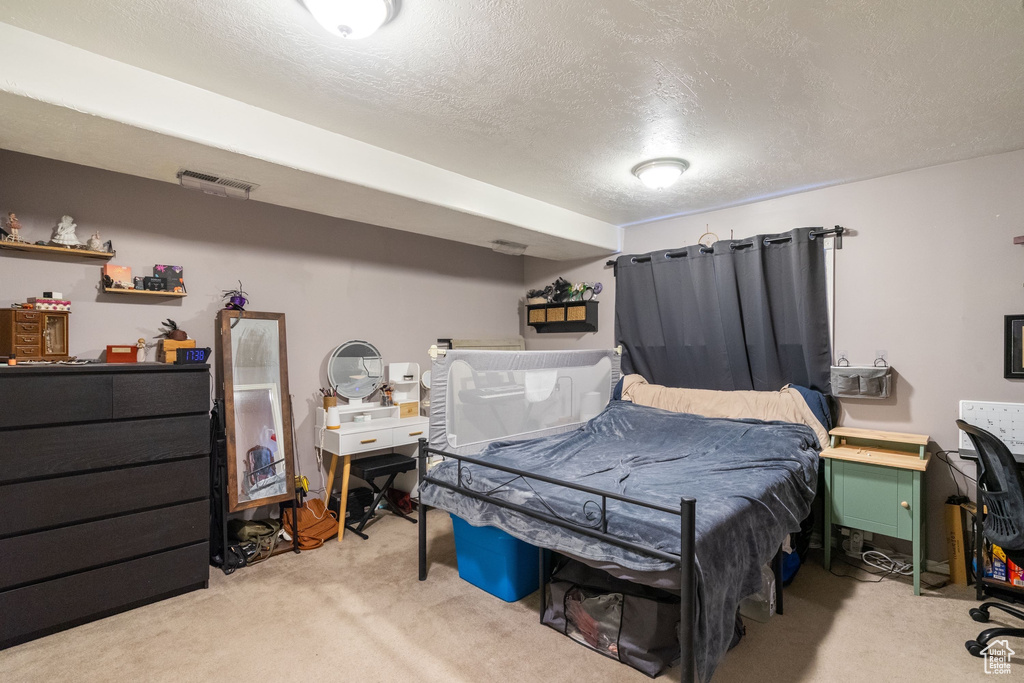 Bedroom with light colored carpet and a textured ceiling