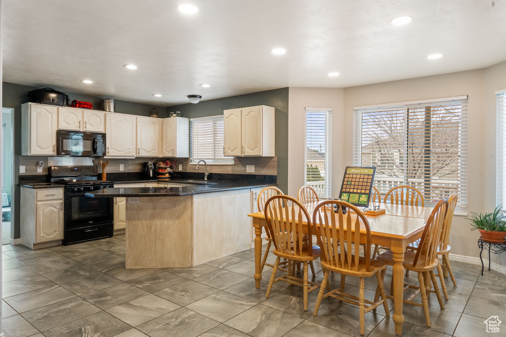 Kitchen with black appliances, a sink, dark countertops, recessed lighting, and baseboards