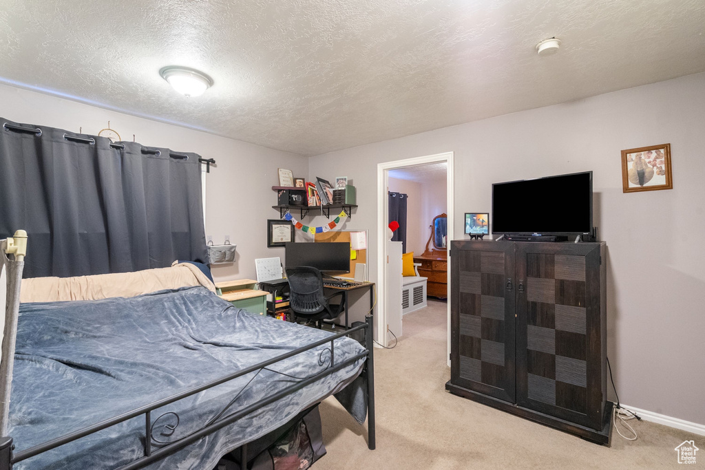 Bedroom with light colored carpet, baseboards, and a textured ceiling