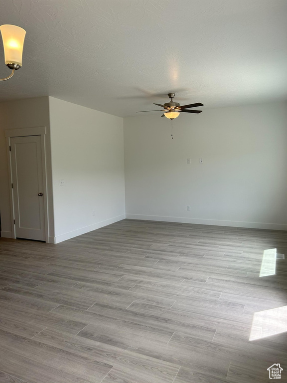 Spare room with ceiling fan, baseboards, and light wood-style floors