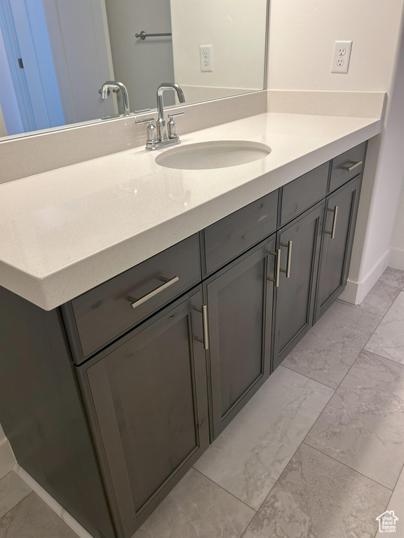 Bathroom featuring vanity, marble look tile flooring, and baseboards