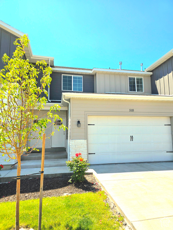 View of front of house with board and batten siding, driveway, and a garage