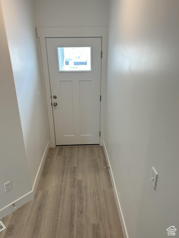 Doorway with light wood-style floors and baseboards